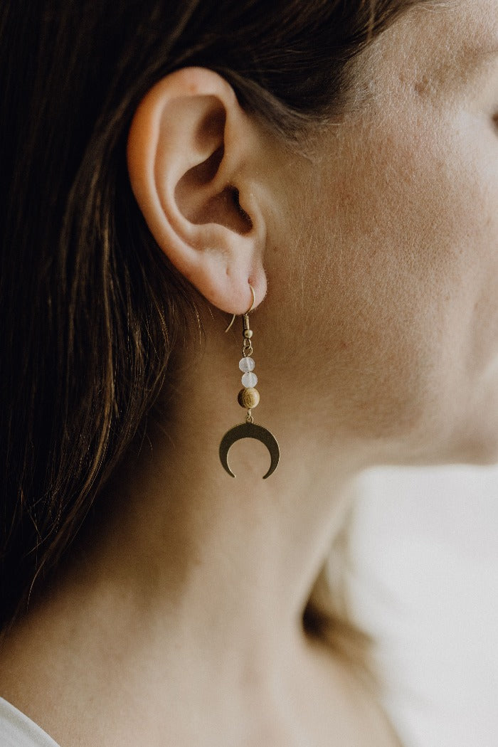 Frau mit Ohrringen aus Rosenquarz-Perlen und Mond-Anhänger aus Messing.